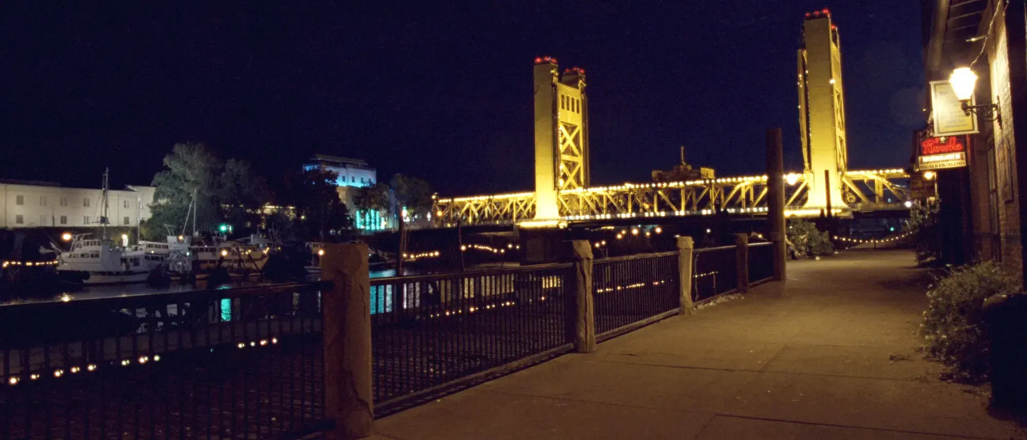 The Sacramento riverfront at night, the gold lift bridge glowing over black water