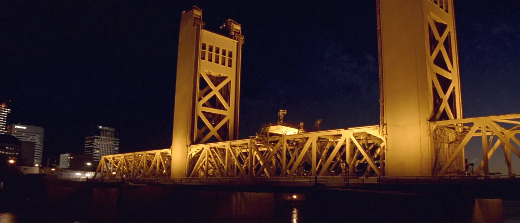 The gold-lit Tower Bridge over the Sacramento River at night